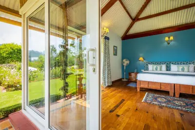 a bedroom with a bed and a large window at amã Stays & Trails Raven's Nest , Kotagiri in Kotagiri