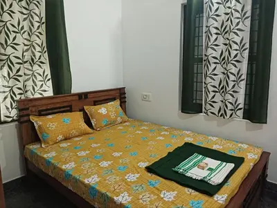 a bedroom with a bed with a comforter on it at BHASURI SERVICED VILLA in Varagampadi