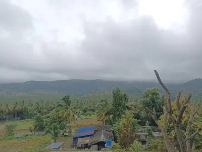a house in a field with mountains in the background at BHASURI SERVICED VILLA in Varagampadi