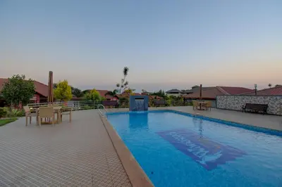 a large swimming pool with a table and chairs at Woodstock Resorts in Madikeri
