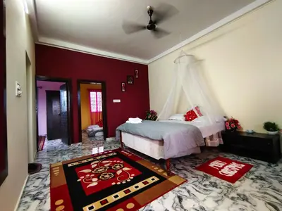 a bedroom with a bed and a red wall at Mannat Inn Homestay (Mysore) in Mysore