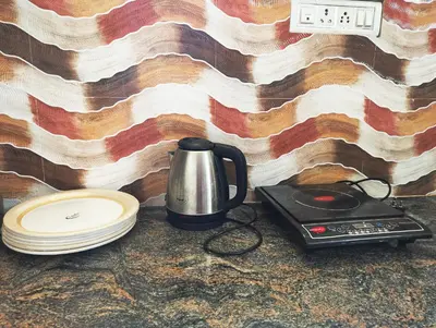 a coffee pot and plates on a counter next to a wall at Mannat Inn Homestay (Mysore) in Mysore