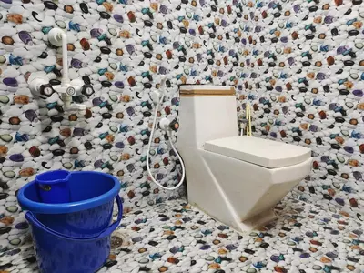 a bathroom with a toilet and a wall covered in tiles at Mannat Inn Homestay (Mysore) in Mysore