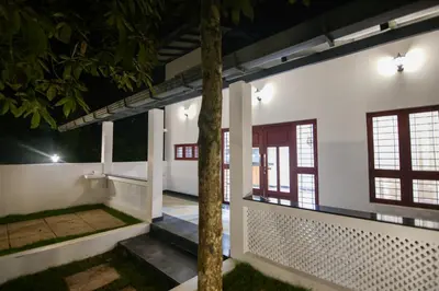 a white house with a porch at night at B'camp Resorts & Homestays in Wayanad