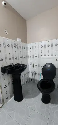 a bathroom with a black toilet and a sink at Heath Cote in Ooty