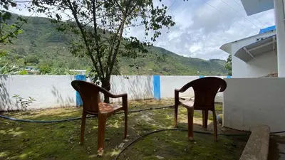 two chairs sitting in the grass next to a building at La Flora kodaikanal in Kodaikānāl