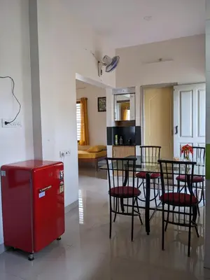 a kitchen and a dining room with a red refrigerator at Athreyas@60/A in Mysore