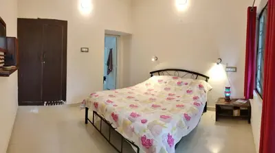 a bedroom with a bed with a floral bedspread on it at Raintree Garden in Mysore