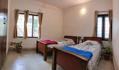a bedroom with two beds and two windows at Raintree Garden in Mysore