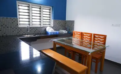 a kitchen with a table and chairs and a sink at WAYANAD OASIS VILLa in Kalpetta