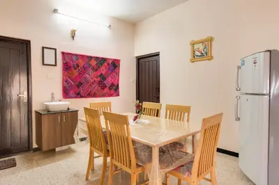 a kitchen with a table and chairs and a refrigerator at Corner Stay Serviced Apartment-Racecourse in Coimbatore
