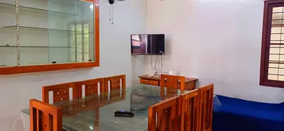 a room with a glass table and a tv at Kalpetta Peace Villa in Kalpetta