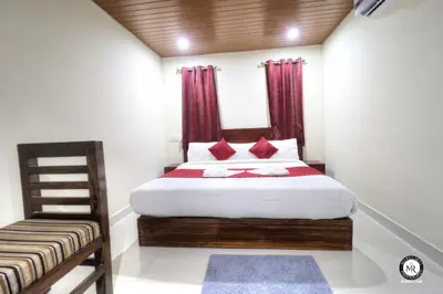 a bedroom with a bed with red curtains and a chair at Coorg Avani Holiday Inn in Madikeri