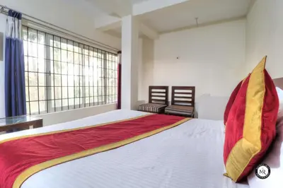 a bedroom with a large bed with a red and yellow blanket at Coorg Avani Holiday Inn in Madikeri