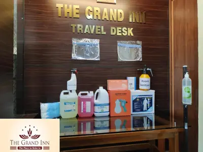 a sign for the grand inn travel desk with products on a table at The Grand Inn Mysore in Mysore