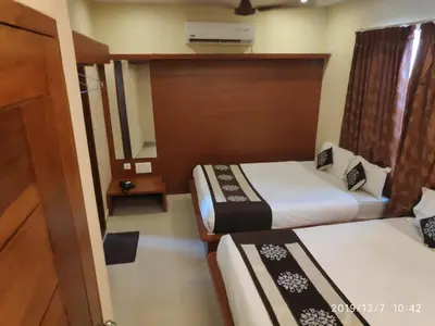 a hotel room with two beds and a window at The Grand Inn Mysore in Mysore