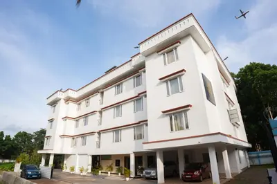 a large white building with a plane in the sky at Daffodils Luxury Airport Suites in Angamali
