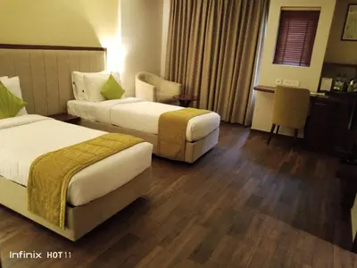 a hotel room with two beds and a table at Woodbine Foliage in Malappuram