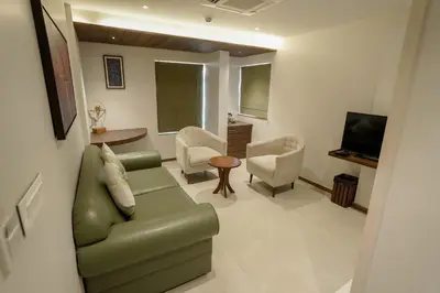 a living room with a green couch and chairs at Woodbine Foliage in Malappuram