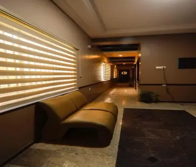 a couch in a hallway with a window with blinds at Hotel Vinayaga Excellenciy Tiruppur in Tiruppūr
