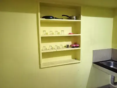 a kitchen with a shelf with dishes on it at Pebbles in Kozhikode