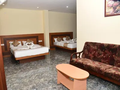a living room with two beds and a couch at Sanjose Residency in Virajpet