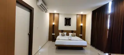 a hotel room with two beds and a sliding door at Sanjose Residency in Virajpet