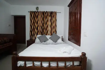 a bed with black and white pillows in a bedroom at Wayanad Palm Grove Retreat G Floor in Sultan Bathery