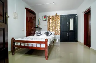 a bedroom with a bed and a black cabinet at Wayanad Palm Grove Retreat G Floor in Sultan Bathery