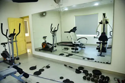 a gym with several exercise equipment and a large mirror at Ivory sea castle in Kozhikode