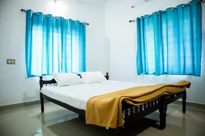 a bedroom with a bed with blue curtains at Padmanabhan's Homestay in Thrissur, Punkunnam in Trichūr