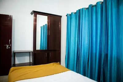 a bedroom with blue curtains and a bed and a mirror at Padmanabhan's Homestay in Thrissur, Punkunnam in Trichūr