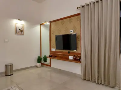 a living room with a television and a curtain at The Cana's Coorg in Ammatti