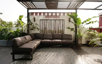 a brown leather couch in a room with plants at Lofterra in Kozhikode
