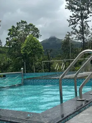 a swimming pool with blue water and mountains in the background at Marina Homestay in Devāla