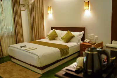a hotel room with a bed and a table at Bamboo Grove in Mānantoddy