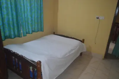 a bedroom with a bed with white sheets and blue curtains at Kalpavruksha Farmstay by StayApart in Madikeri