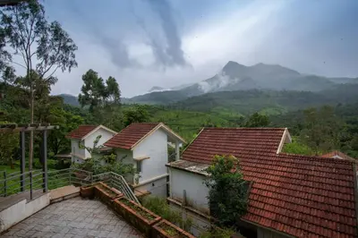 a group of houses with mountains in the background at Dazzle Villa Resort in Kalpetta