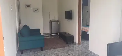 a living room with a blue chair and a television at SHI's Peaceful Oasis near Isha Adiyogi, Kovai Kuttralam Waterfalls & Karunya University in Alāndurai