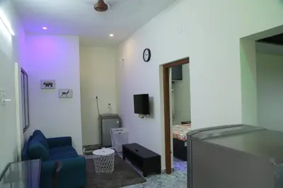 a living room with a blue couch and a bed at SHI's Peaceful Oasis near Isha Adiyogi, Kovai Kuttralam Waterfalls & Karunya University in Alāndurai