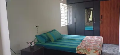 a bedroom with a bed with blue sheets and blue pillows at SHI's Peaceful Oasis near Isha Adiyogi, Kovai Kuttralam Waterfalls & Karunya University in Alāndurai