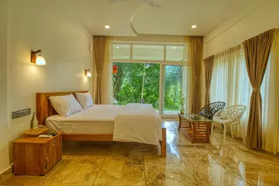 a bedroom with a bed and a large window at Ende Wayanad Resort in Koroth