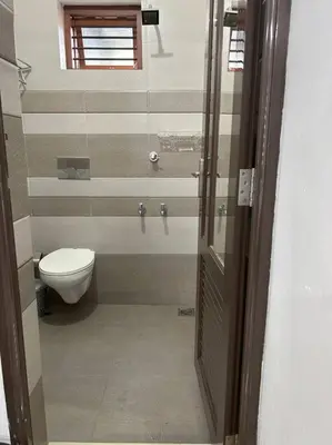 a bathroom with a toilet and a glass door at Saaketh Holiday Home(2) in Kozhikode