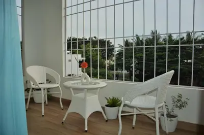 a balcony with chairs and a table and a window at Earth - Luxurious 5 BHK AC Villa at Mysore in Mysore