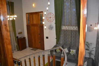 a living room with a couch and a clock on the wall at Earth - Luxurious 5 BHK AC Villa at Mysore in Mysore