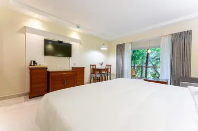 a bedroom with a large white bed and a television at Club Mahindra Golden Landmark, Mysuru in Mysore