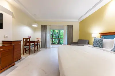 a bedroom with a large bed and a table at Club Mahindra Golden Landmark, Mysuru in Mysore