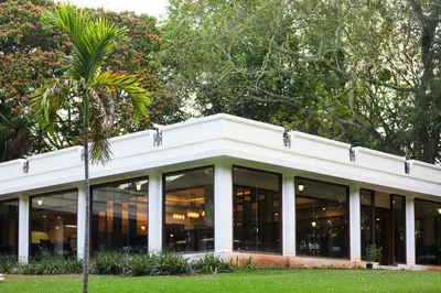 a building with glass windows and a palm tree at Club Mahindra Golden Landmark, Mysuru in Mysore