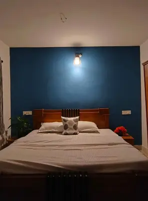 a bedroom with a large bed with a blue wall at Nama-Stay - An escape villa in Ooty