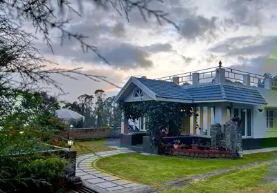a small house with a blue roof on a yard at Nama-Stay - An escape villa in Ooty